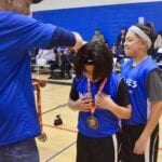 man awarding a medal to a blue team basketball player