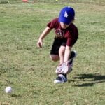boy in a maroon shirt catching a ball