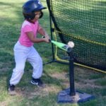 kid with pink shirt practicing tee ball