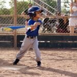 young boy in blue uniform about to hit a ball