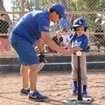 coach teaching a boy in blue uniform
