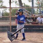 young kid in blue uniform playing tee ball