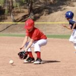 kid in red shirt catching a baseball