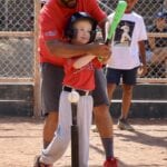 coach teaching a girl about batting