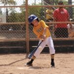 kid with yellow jersey about to hit a low ball