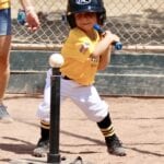 young kid in yellow jersey playing tee ball