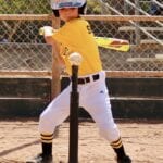 young girl in yellow jersey playing tee ball
