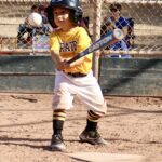boy in yellow uniform about to a baseball ball