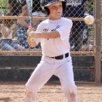 kid in white uniform about to hit an incoming ball