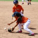 girl in orange uniform catching a ball