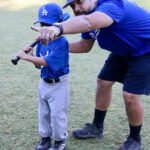 coach teaching a kid in blue uniform