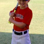 kid in red uniform holding a bat