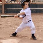 boy holding a bat about to hit a ball