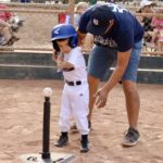 coach teaching a kid how to hit a ball