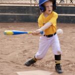 boy in yellow uniform about to hit a ball with a bat