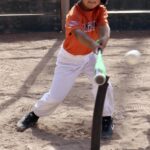 boy in orange shirt practicing how to hit a baseball ball