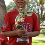 smiling kid with red shirt holding a trophy