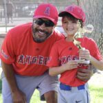 kid with trophy and coach posing for a photo